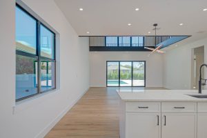Open-concept living space in a custom Naples, FL home featuring floor-to-ceiling windows, modern lighting, and pool view