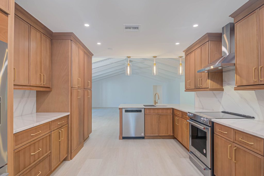 Modern kitchen renovation in Naples, FL with white shaker cabinets, quartz countertops, and stainless steel appliances