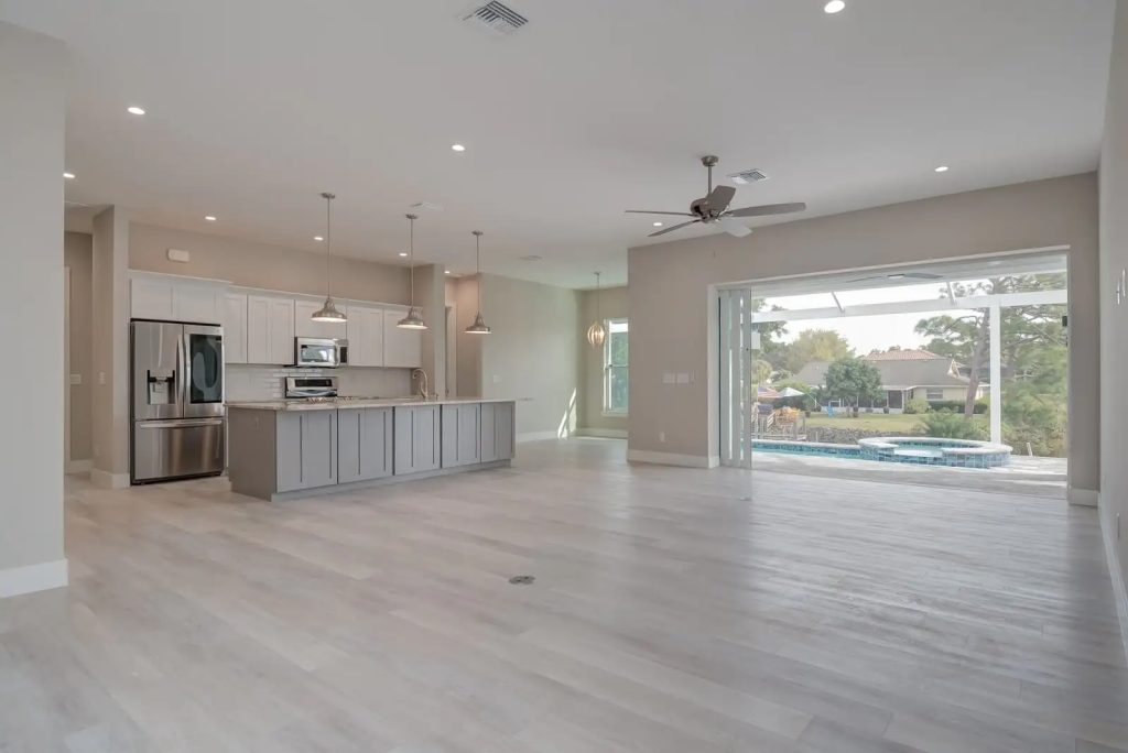 Open concept kitchen and living room remodel by Fortress Custom Builders in Naples FL, featuring custom cabinetry, luxury flooring, and a seamless indoor-outdoor living space.